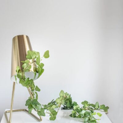 A gold lamp with ivy on top of it.