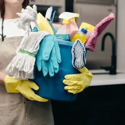 A woman holding a bucket of cleaning supplies.