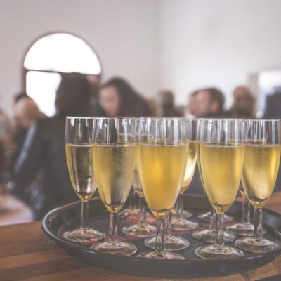 A tray of champagne glasses on a table in front of a group of people.